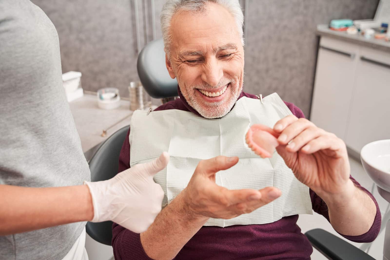 A man holding his dentures, illustrating a removable solution for replacing missing teeth and restoring function