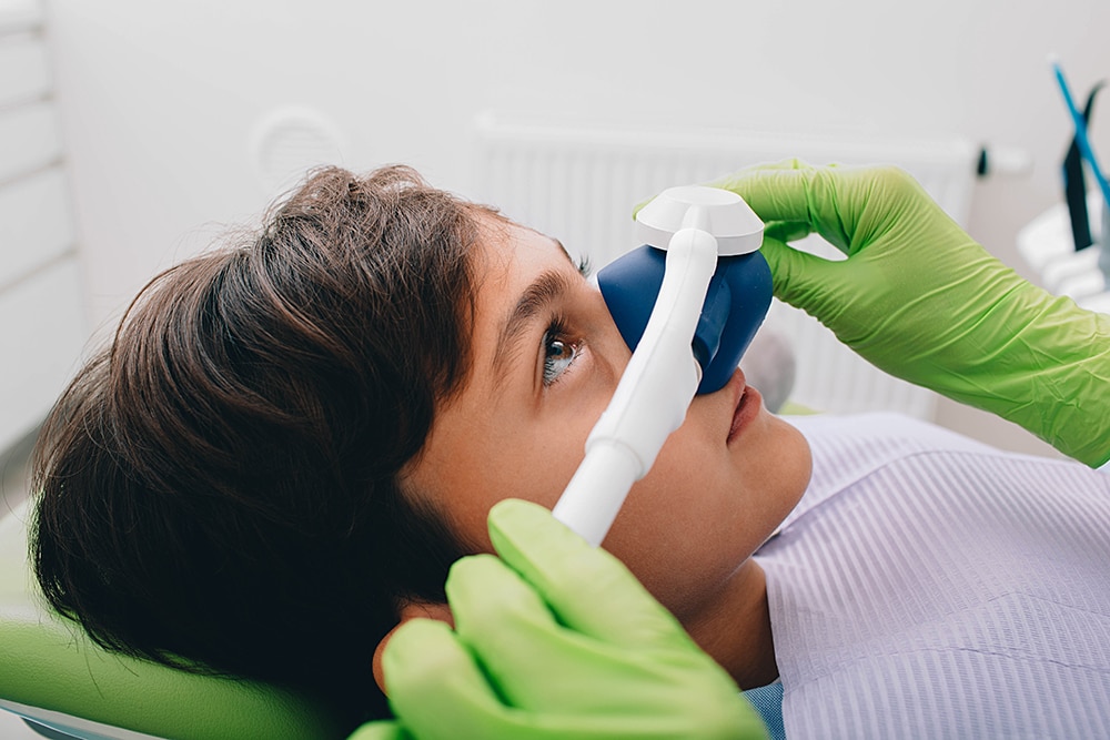 A young boy lying in a dental chair, comfortably receiving nitrous oxide to stay calm during his dental procedure