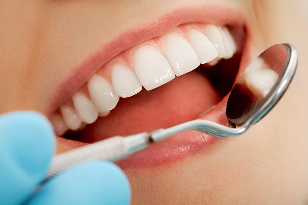 Individual inspecting their teeth with a toothbrush, emphasizing the role of dental bonding in maintaining a healthy smile