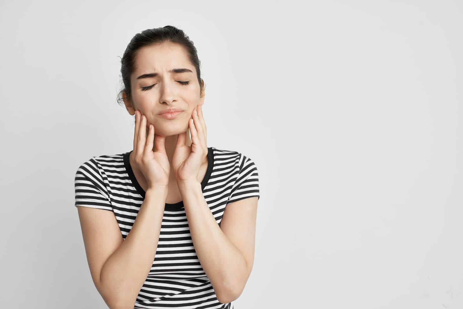 A woman holding her hands to her face, expressing emotion, in a calming environment associated with MAGO Therapy