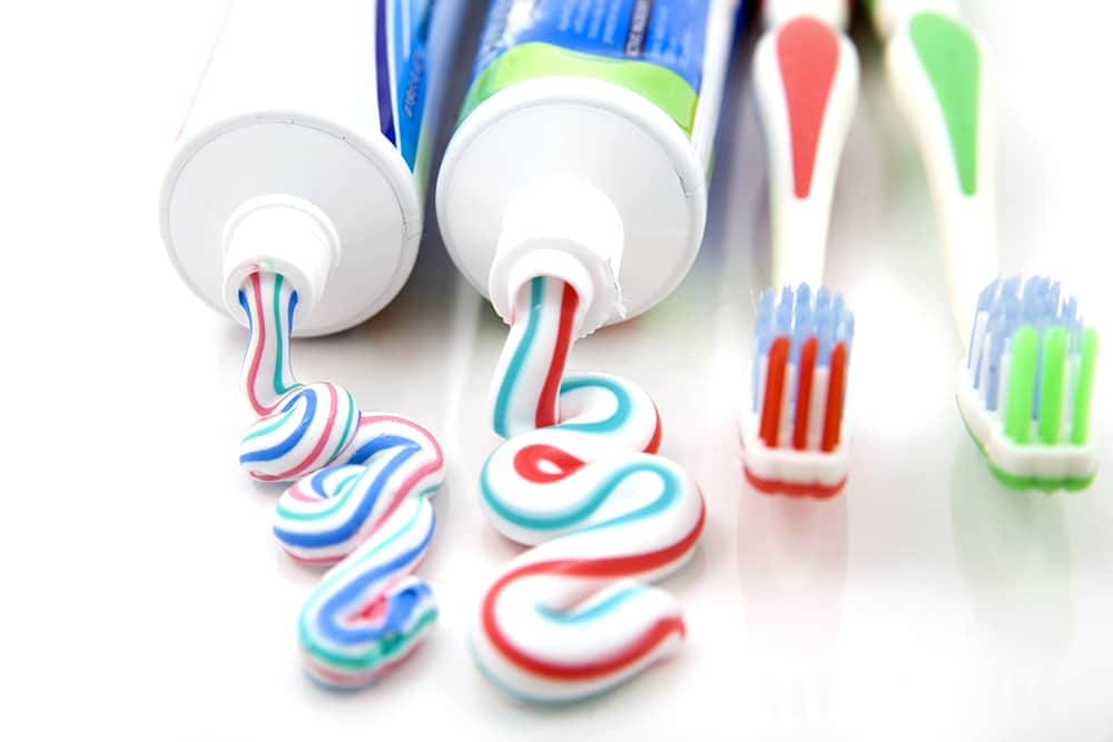 Two toothbrushes and two toothpaste tubes displayed, representing fluoride treatments for cavity prevention and oral health